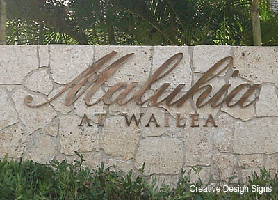 Maluhia - Brass letters on white coral wall.